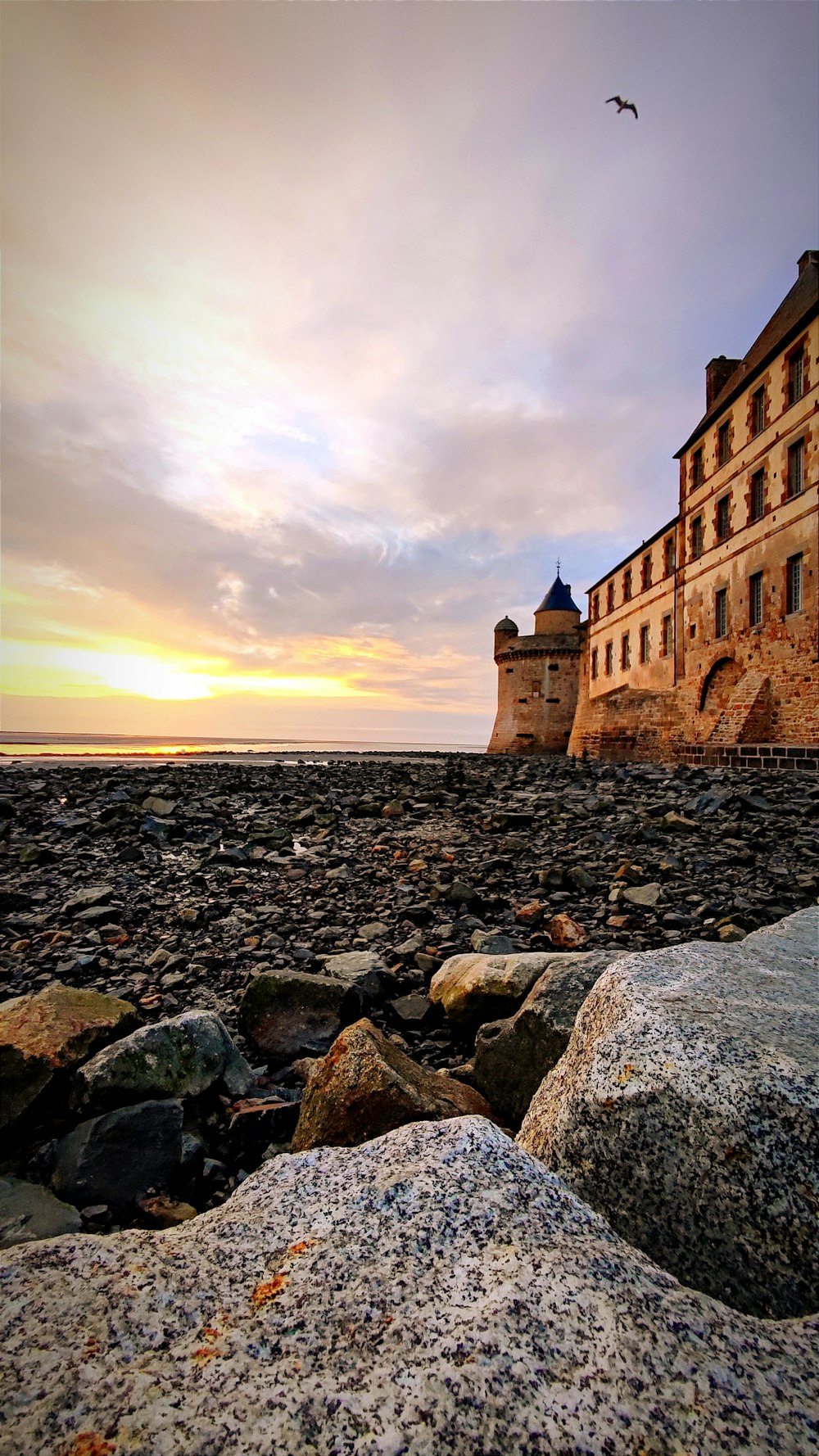 a large building sitting on top of a rocky beach