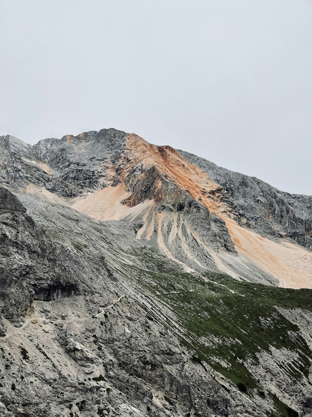 a mountain covered in snow and rocks under a cloudy sky