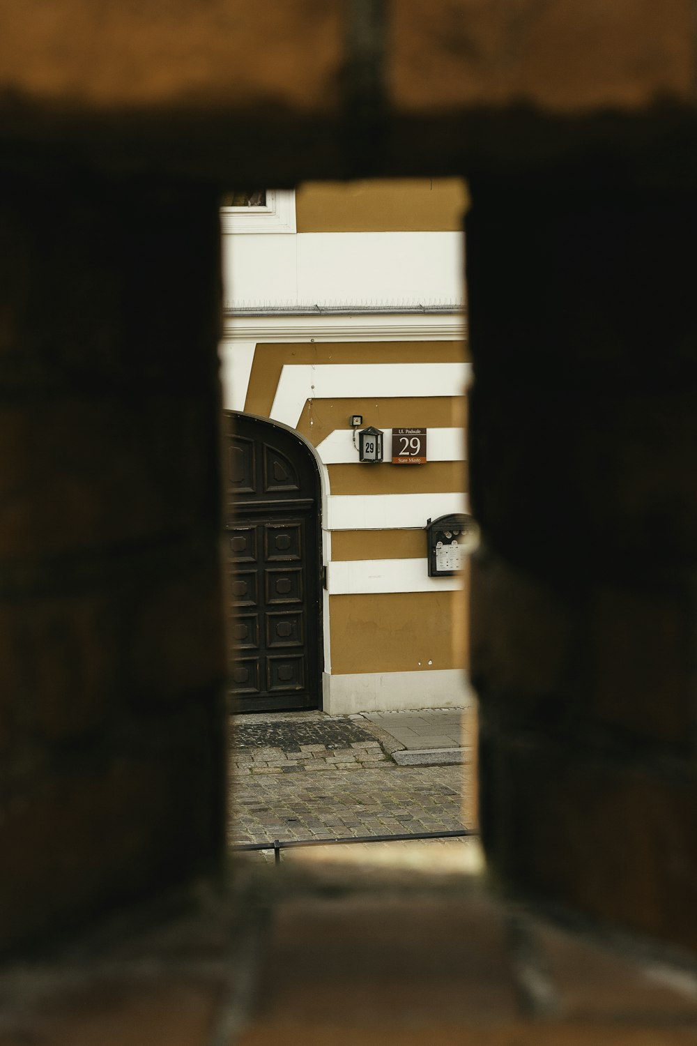 a view of a building through a hole in a brick wall