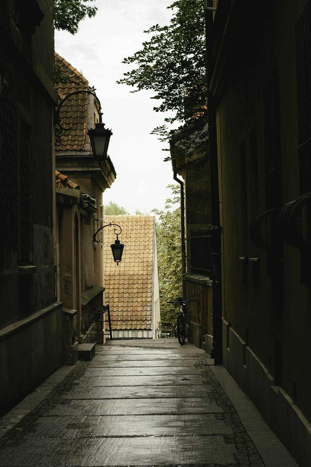 an alley way with a lamp on the side of it