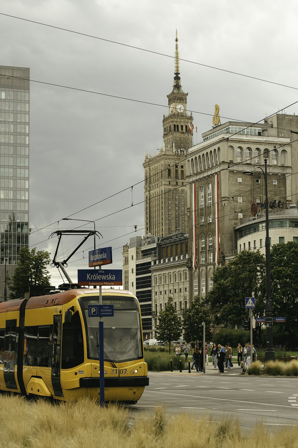 a yellow bus driving down a street next to tall buildings