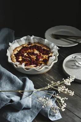 Freshly baked berry tart with glossy fruit topping on a wooden table.