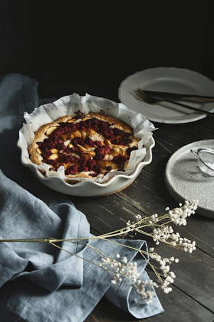 Close-up of a freshly baked fruit tart with vibrant berries and a golden crust on a rustic wooden table.