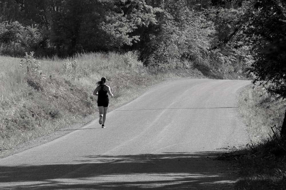 a woman walking down a road in a black and white photo