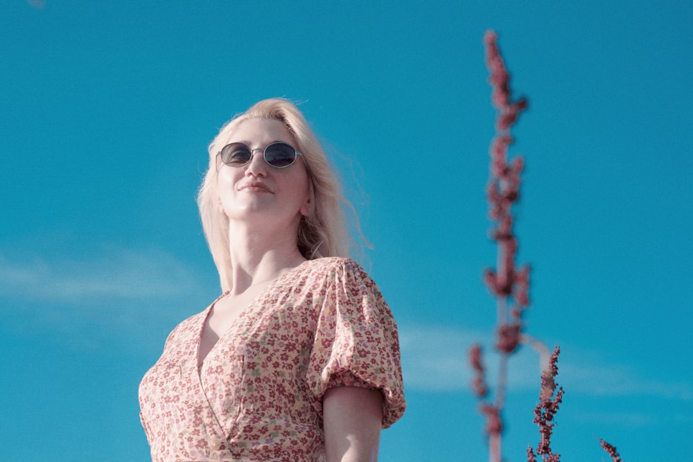 a woman with blonde hair and sunglasses standing in front of a blue sky
