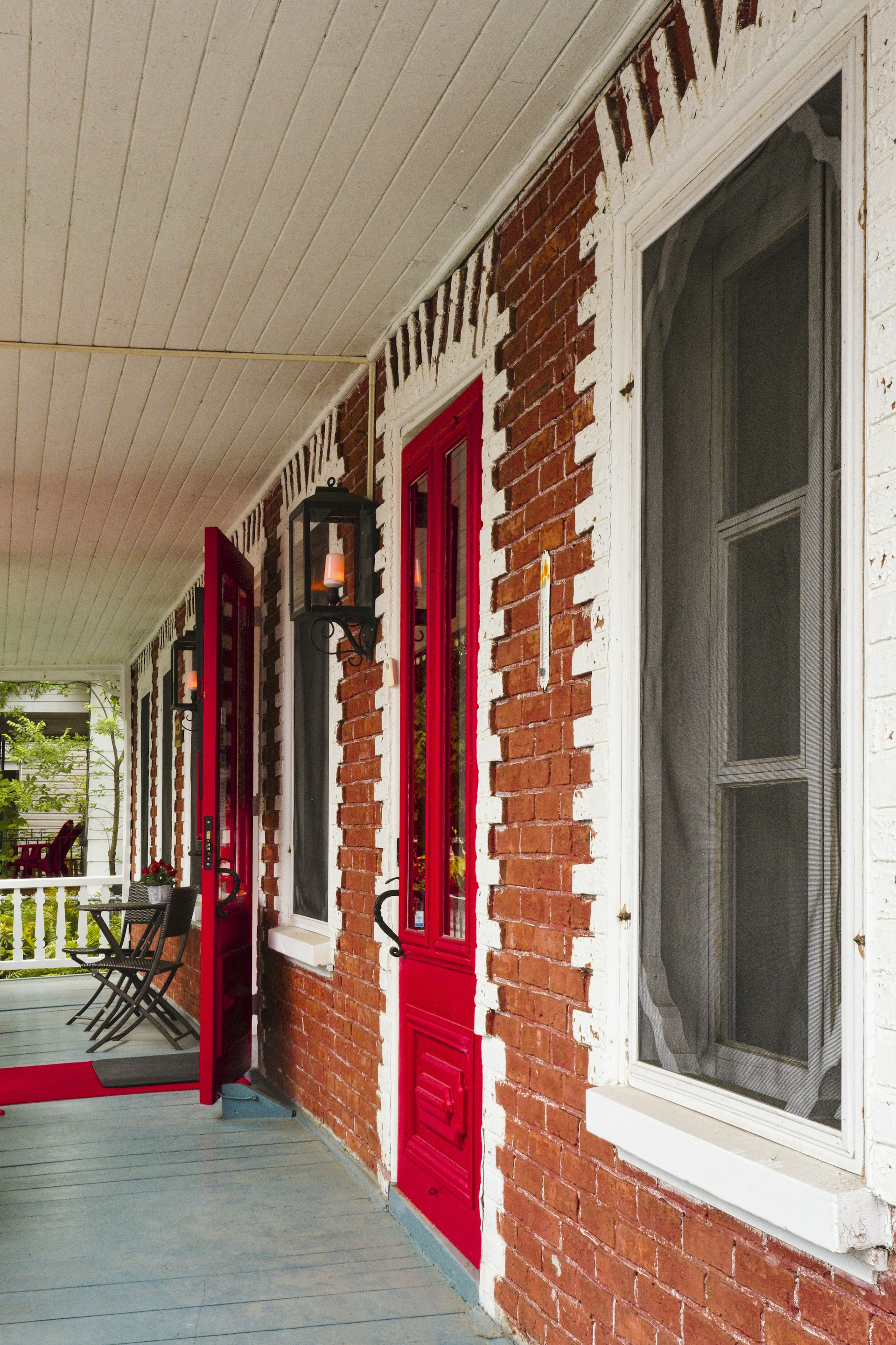 a porch with a red door and two chairs