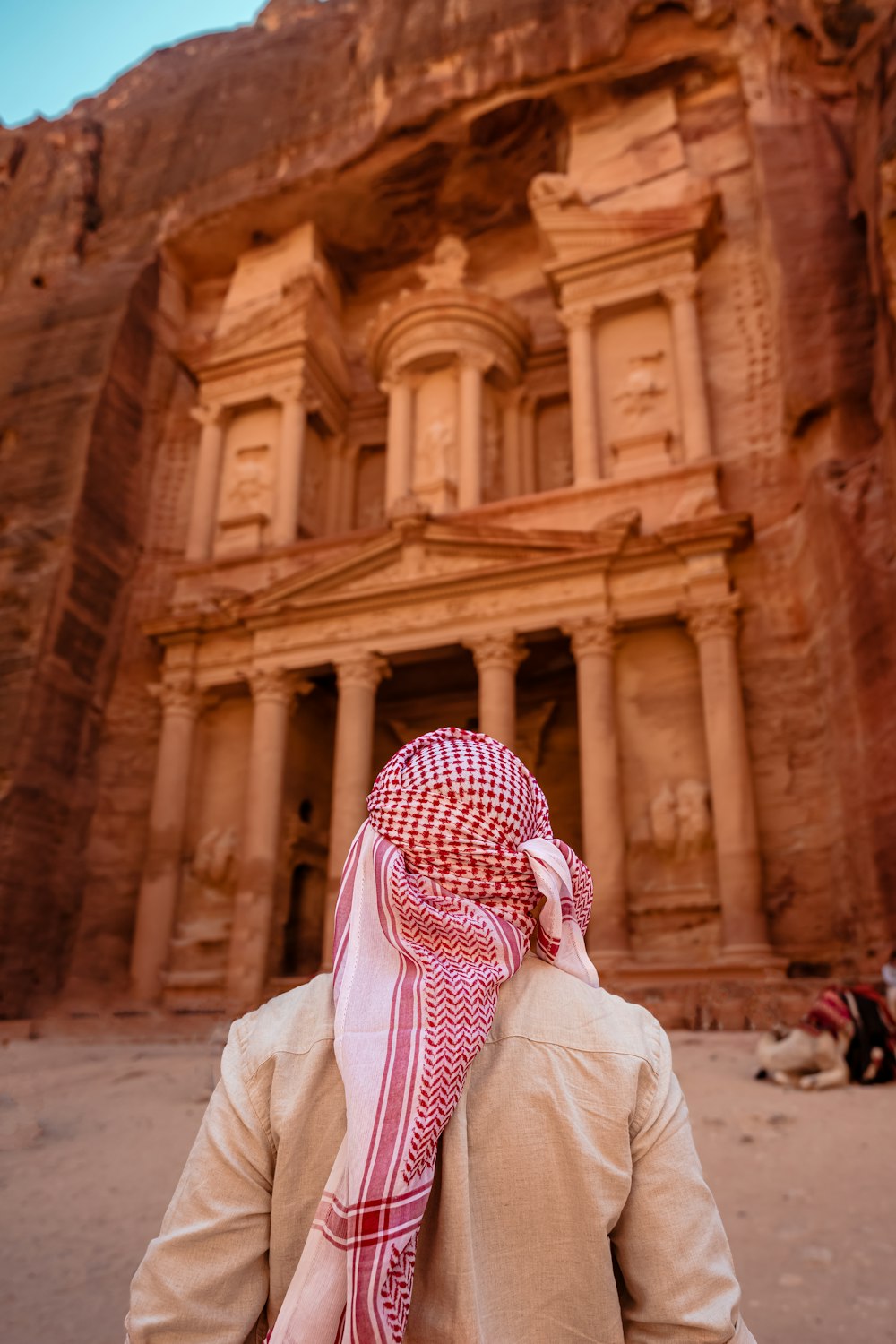 a person wearing a red and white scarf standing in front of a building