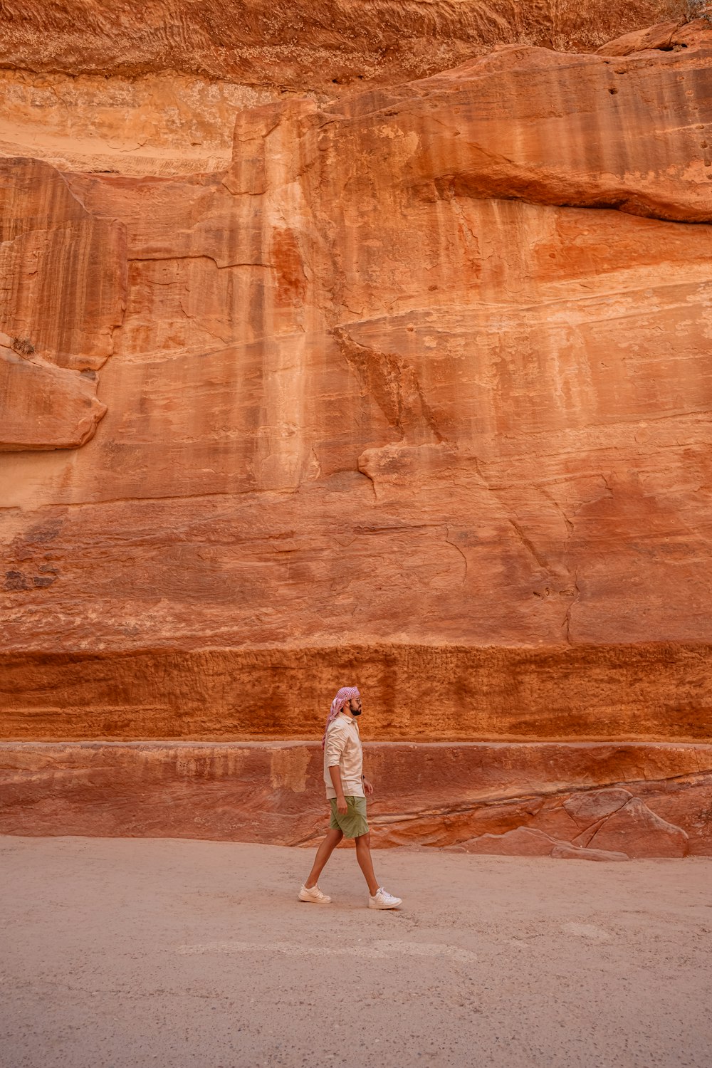 a person walking in front of a large rock formation