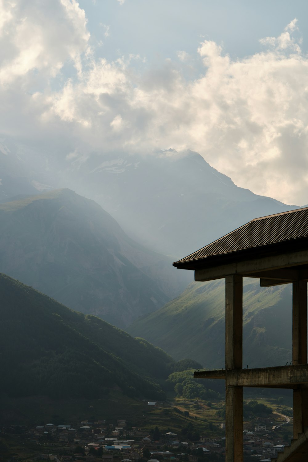 Una vista de una cadena montañosa con una estructura de madera en primer plano
