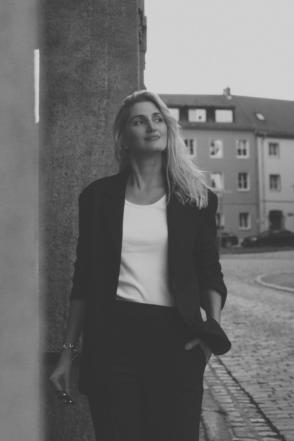 a woman leaning against a wall on the side of a street