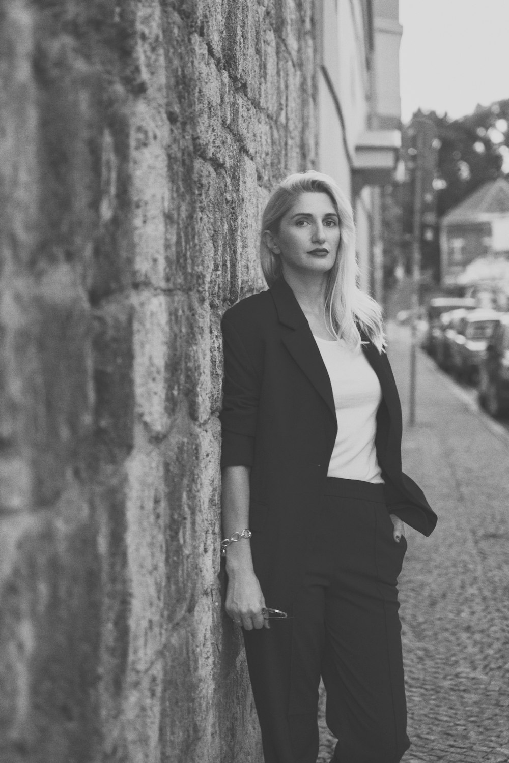 a woman leaning against a brick wall