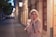 a woman standing on the side of a street next to a building
