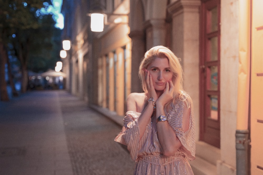 a woman standing on the side of a street next to a building