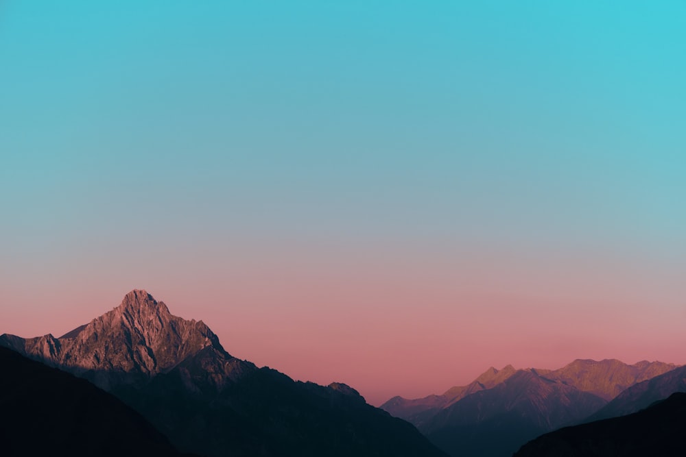 a mountain range with a pink sky in the background