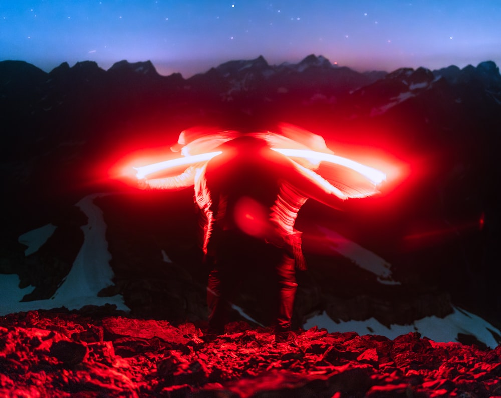 a man standing on top of a rocky mountain under a red light