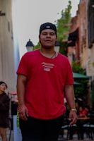 A casual street style shot showing a person wearing a bright red cap against an urban backdrop.