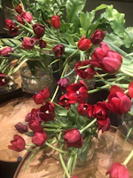 Bright tulips in assorted colors displayed in a modern glass container on a wooden table.