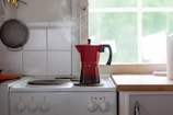 a red coffee pot sitting on top of a stove