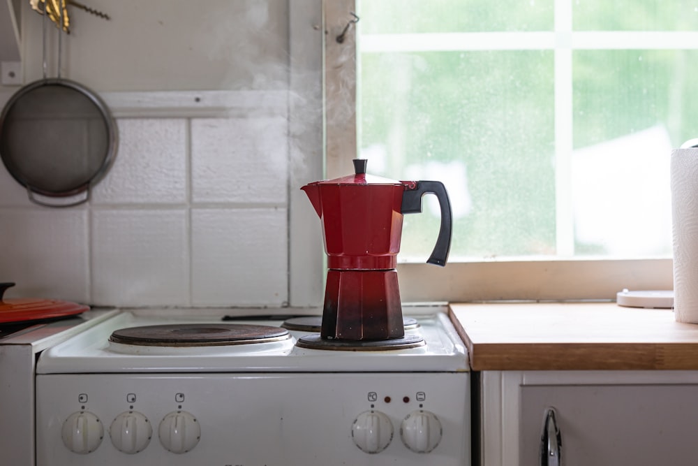 eine rote Kaffeekanne, die auf einem Herd sitzt