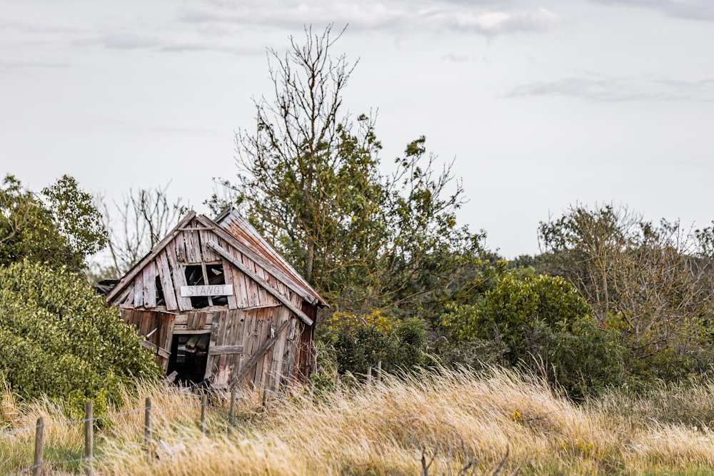 an old run down barn in the middle of a field