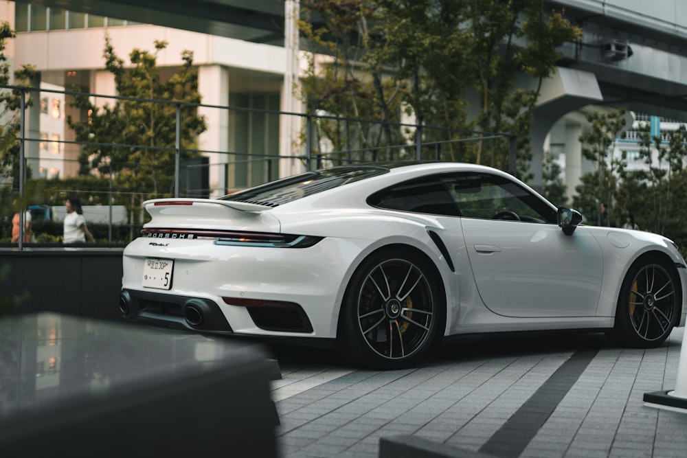 a white porsche sports car parked in front of a building