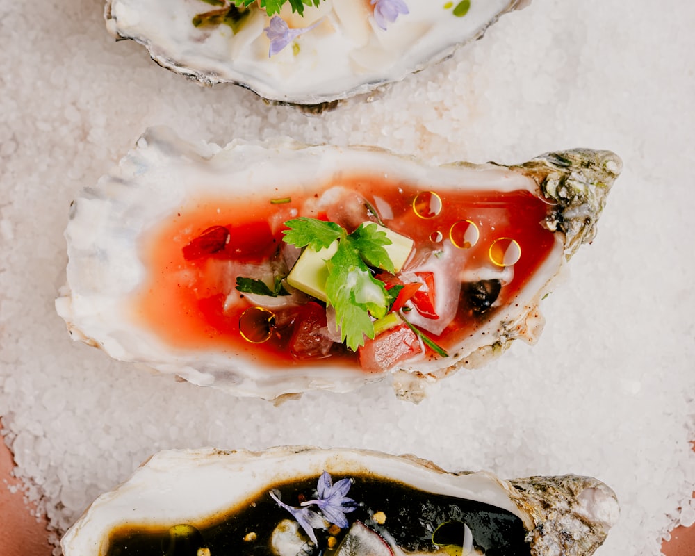 three oysters on ice with a garnish on top