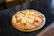 A warm, golden pizza pretzel topped with melted mozzarella and pepperoni on a rustic wooden board.