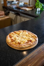 A cozy kitchen counter with fresh pizza ingredients and a handwritten note inviting contact.