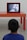 A child is facing away from the camera, watching a television on an orange table in a minimalist, modern setting. The child is wearing a blue shirt, and the television screen shows a blurred image.