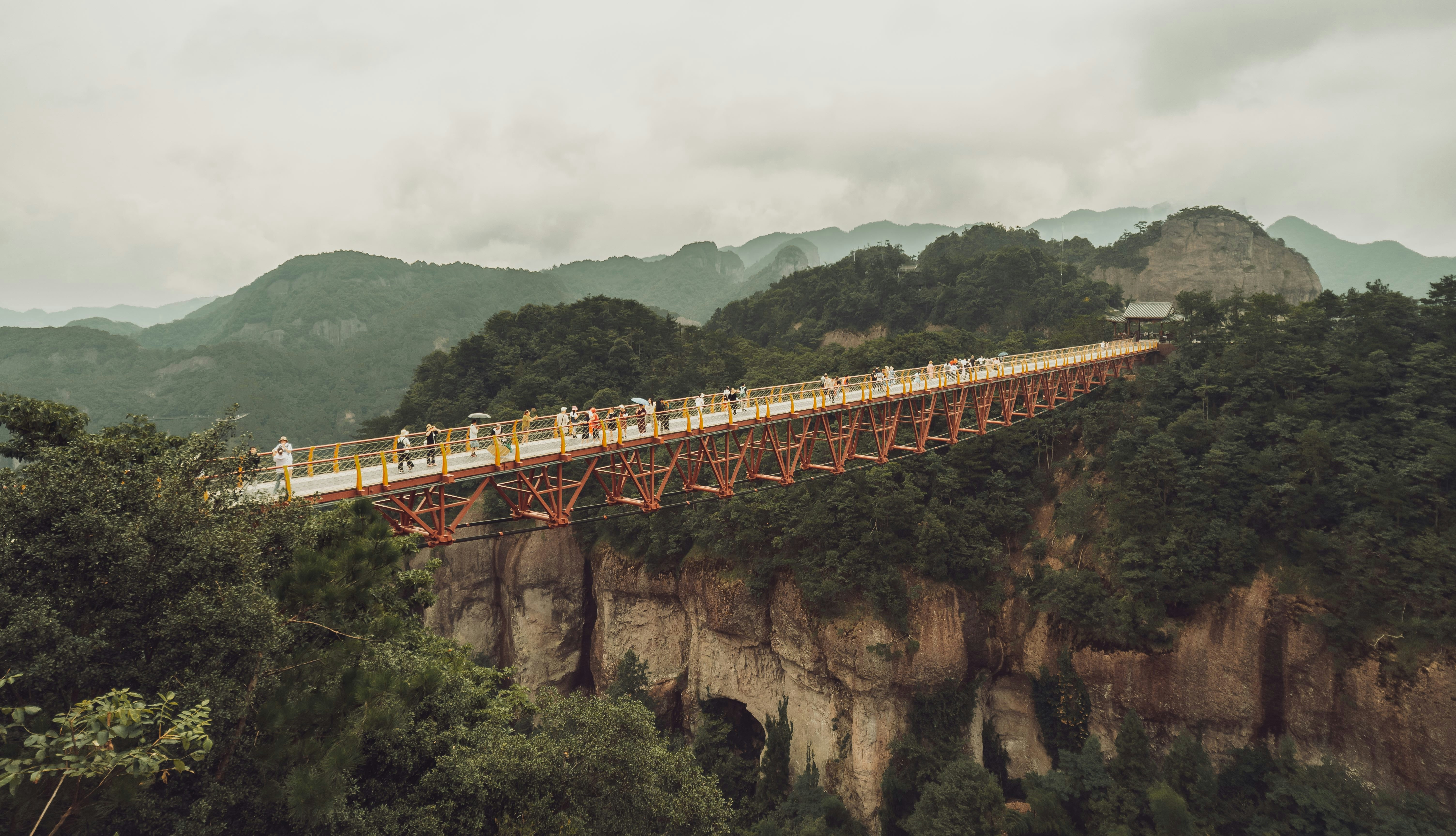 a group of people on a bridge over a mountain