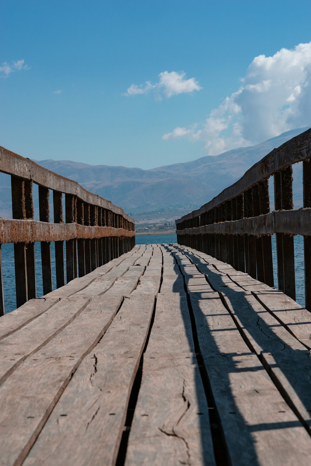a long wooden dock with mountains in the background