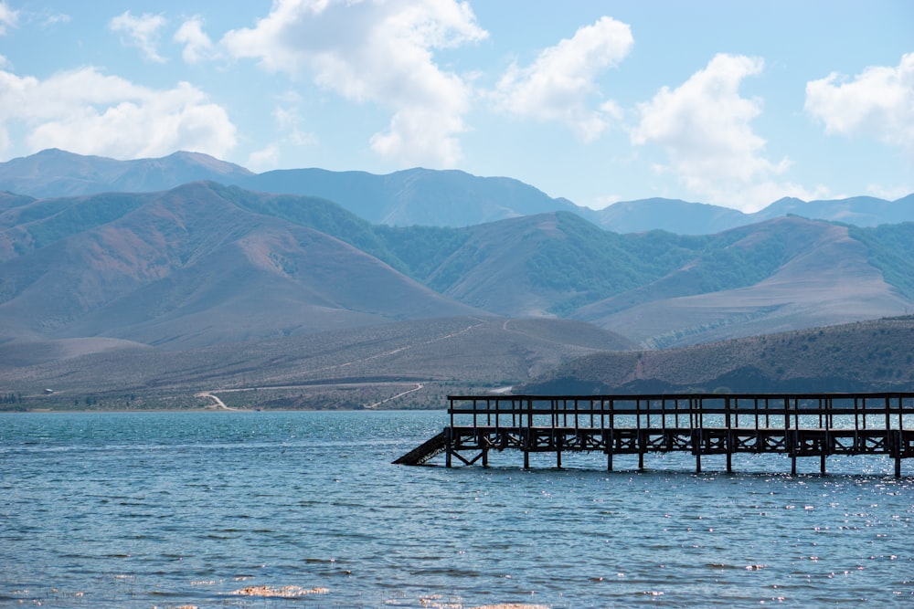 a pier in the middle of a lake with mountains in the background
