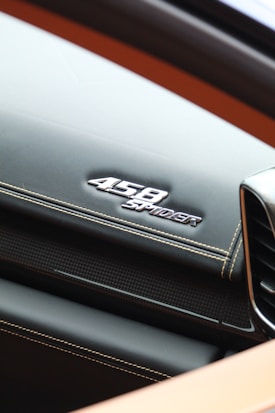 A sleek dashboard with a logo displaying the name '458 Spider' in shiny metallic lettering. The stitching and textured surfaces add a luxurious feel to the design.