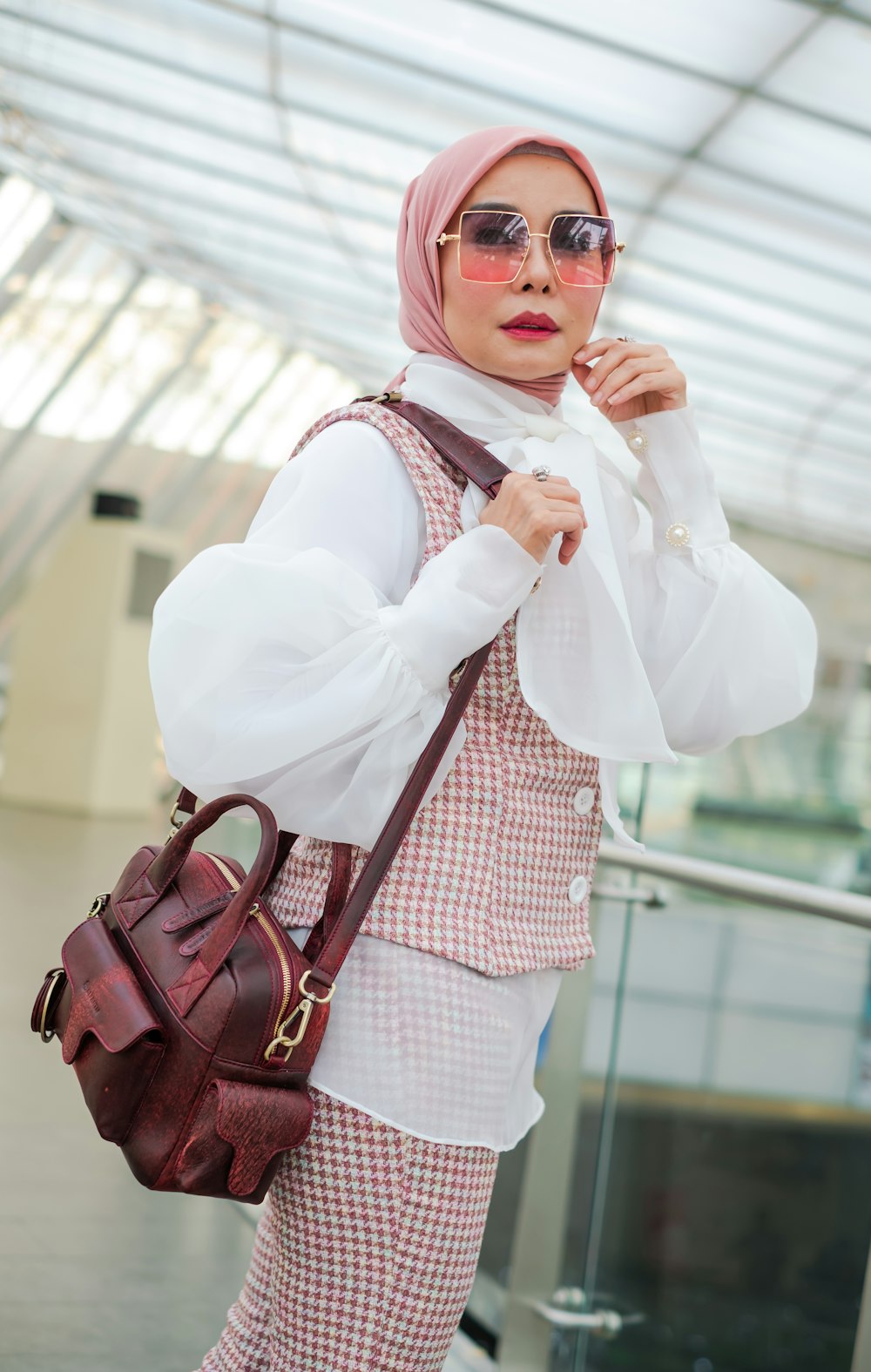 a woman with a pink hijab is holding a brown purse