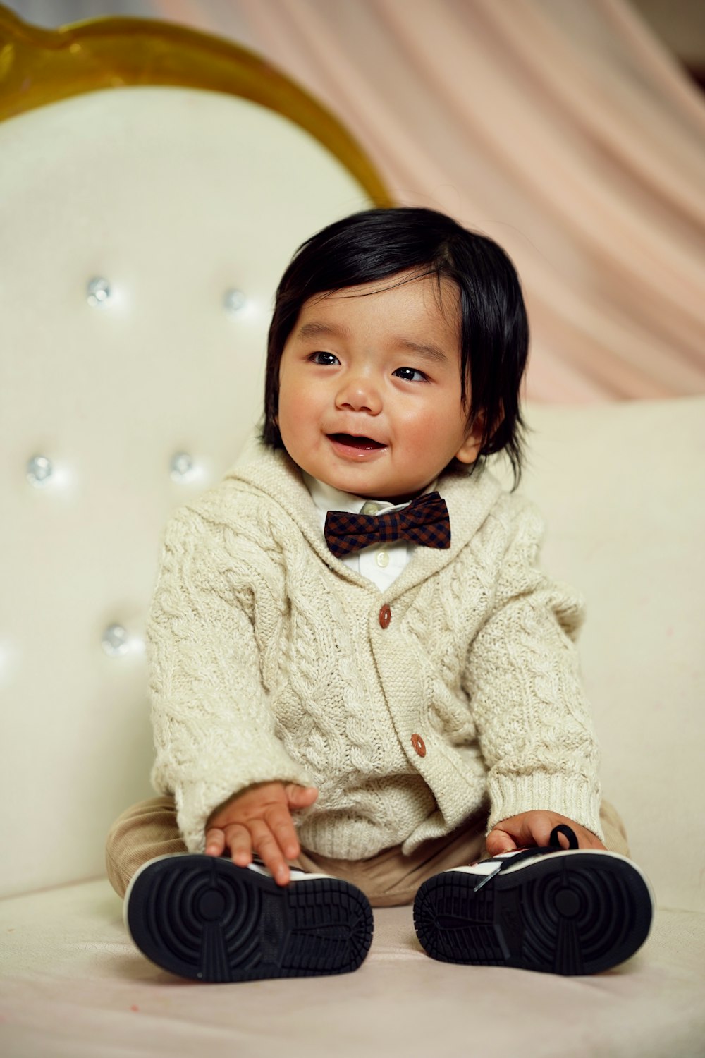a baby wearing a bow tie sitting on a white chair