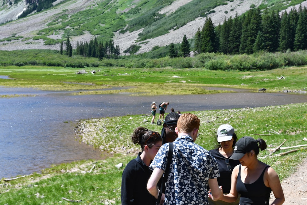 a group of people standing next to a lake