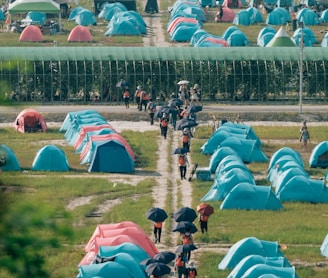 a group of people walking down a dirt road next to tents