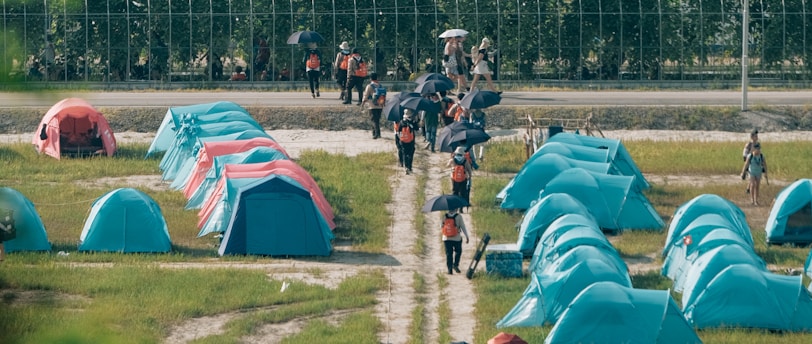a group of people walking down a dirt road next to tents