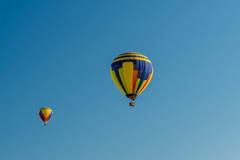 a couple of hot air balloons flying through a blue sky