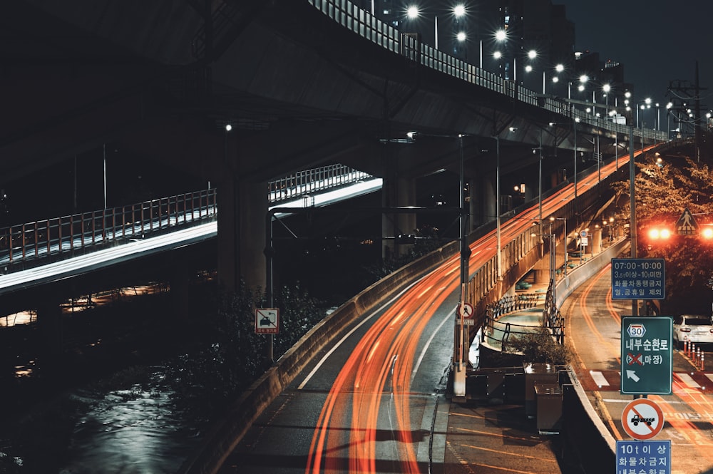 a city street at night with a bridge in the background