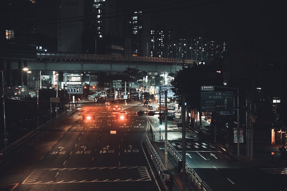 a city street at night with a bridge in the background