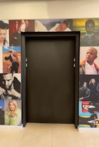 An elevator door is surrounded by various photographs of celebrities and musicians. The images include close-ups and artistic shots, capturing a mix of expressions and poses. The wall serves as a creative backdrop to the central elevator door.