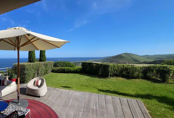 A cozy coastal patio set arranged on a sunlit deck overlooking the ocean.