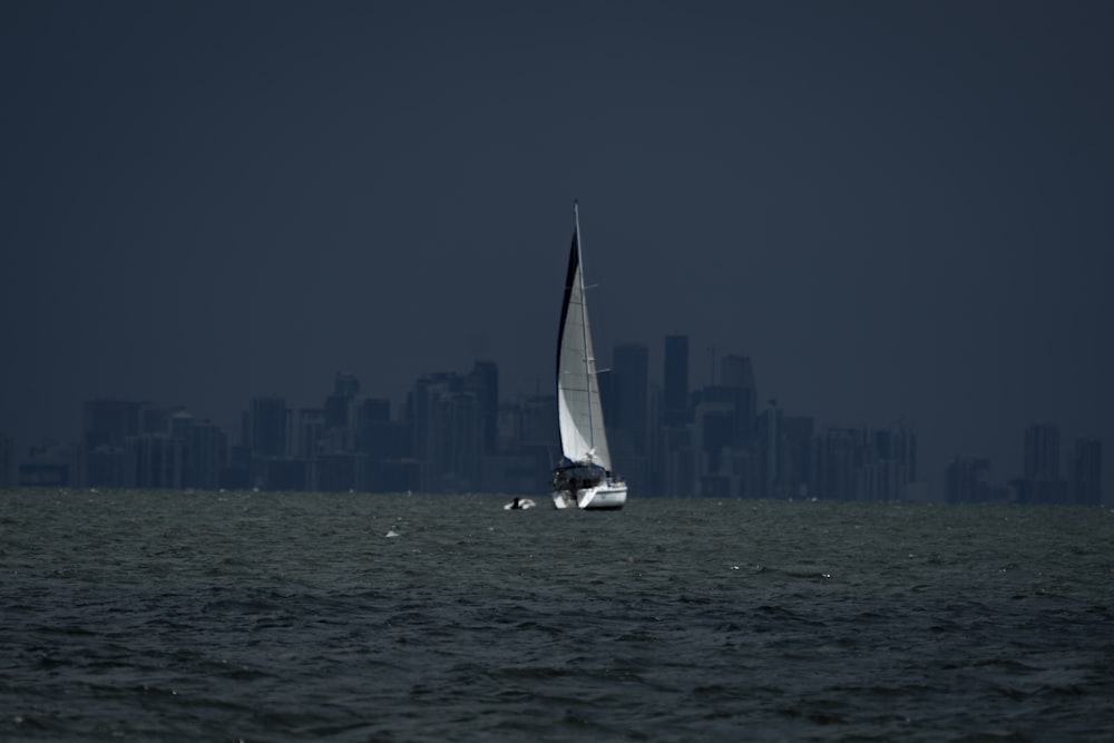 a sailboat in the ocean with a city in the background