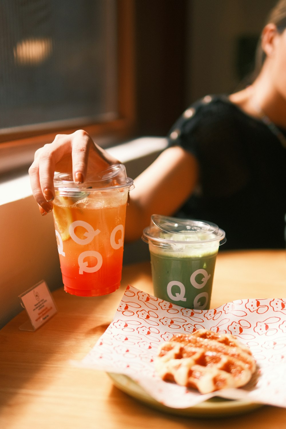 a person sitting at a table with a drink and a cookie