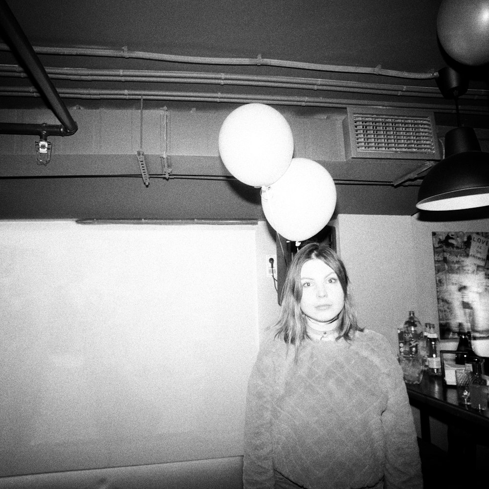 a black and white photo of a woman with balloons on her head