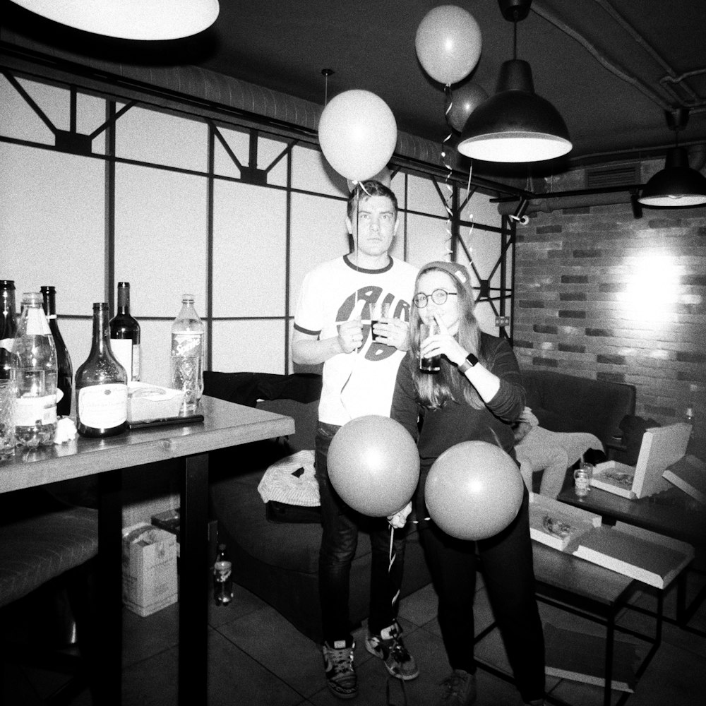 a man and a woman standing in a room with balloons