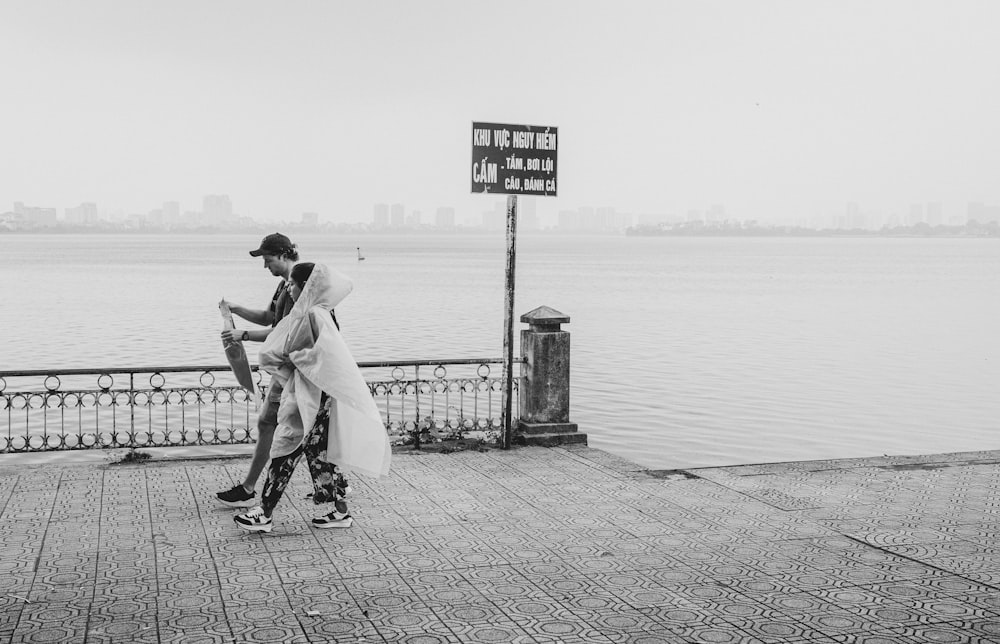Un hombre y una mujer caminando en un muelle junto al agua