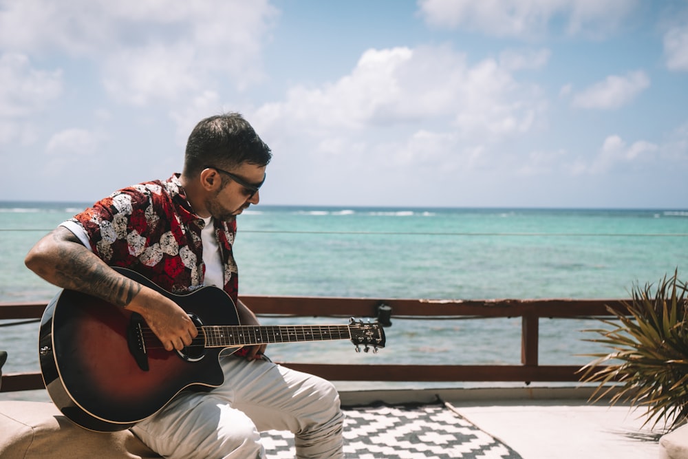 a man sitting on a ledge playing a guitar