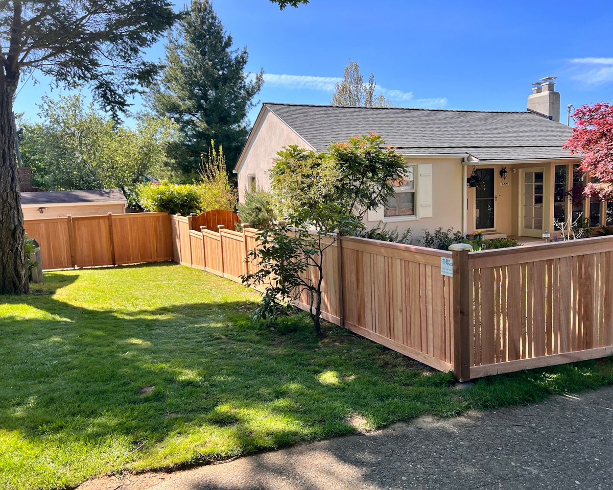 Finished cedar fence and gate in front of a house yard